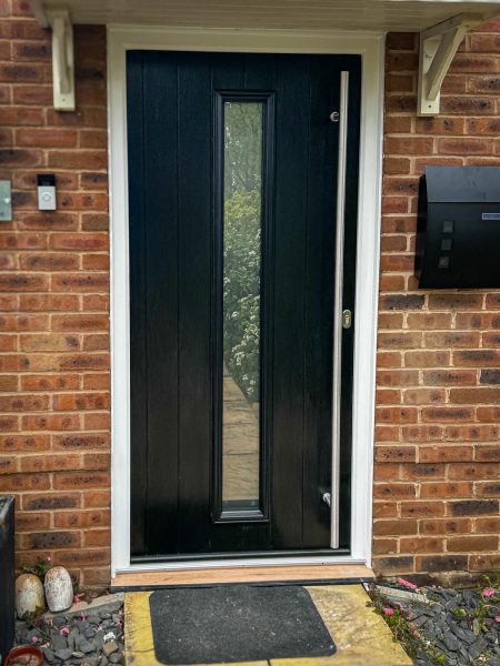 Black composite door in white frame with long bar handle