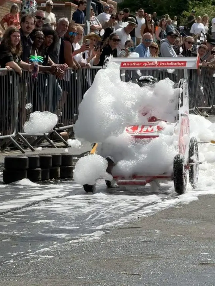 A soapbox kart heavily covered in soap suds making its way down the track