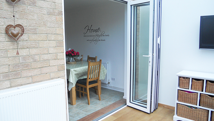 Bi-folding-door-from-house-to-conservatory.jpg Bi-fold doors from house to a conservatory in white